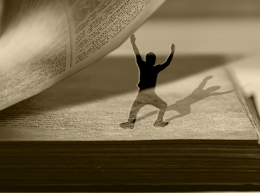 Silhouette d'une personne projetée sur un livre ouvert, comme en train de danser entre les pages