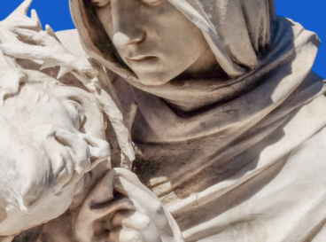 Détail d’une sculpture représentant une scène de piéta, avec une femme en voile tenant un visage